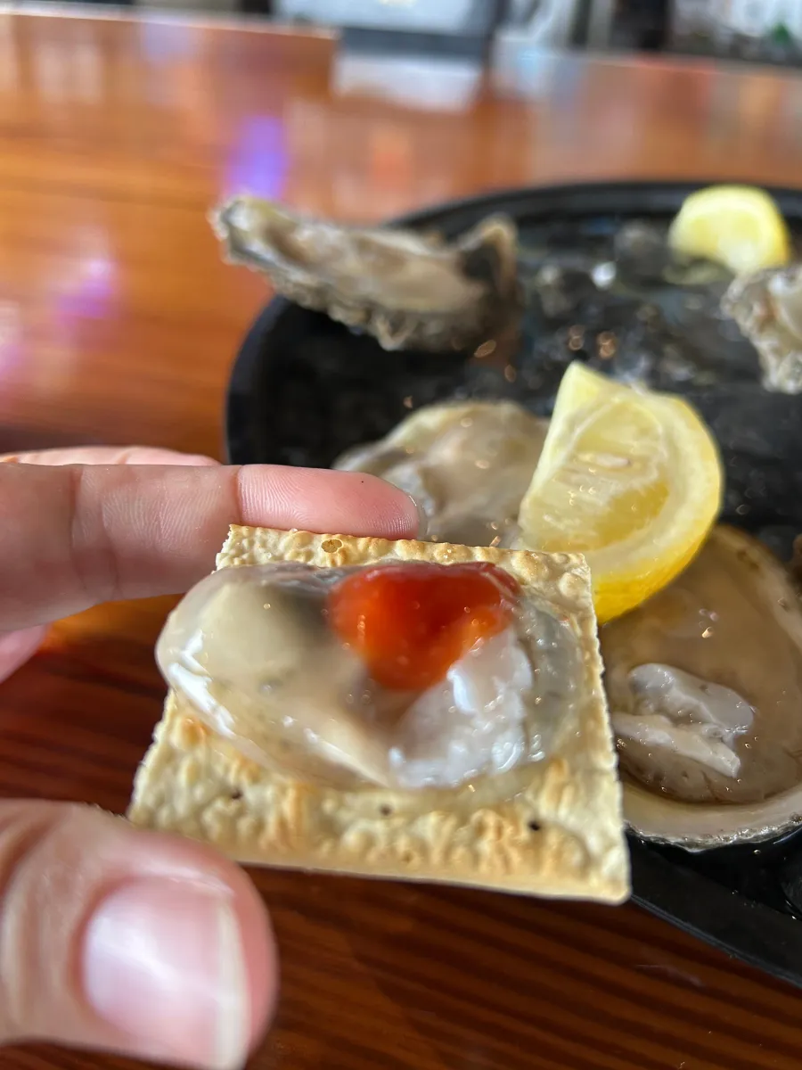 Fresh raw Gulf oyster with cocktail sauce on a cracker at Hunt's Oyster Bar in Panama City, Florida.