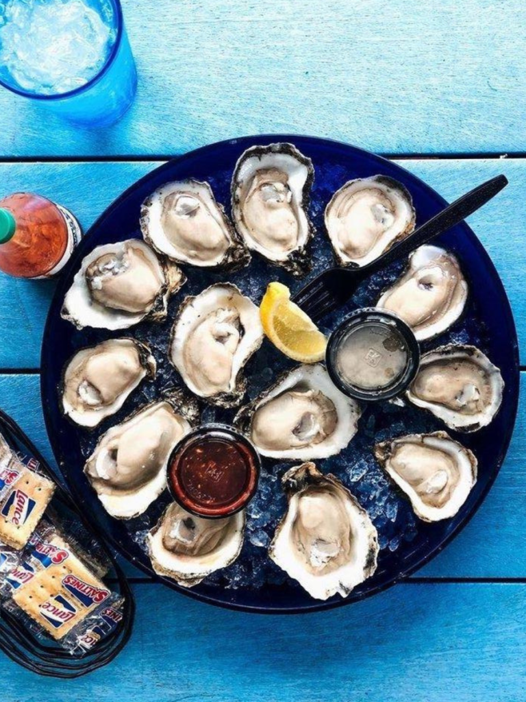 National Oyster Day Shines Bright with the Golden Oyster at Hunt’s in Panama City: A Truly Unforgettable Celebration 8 A fresh platter of raw oysters on ice served with cocktail sauce, crackers, and lemon wedges for National Oyster Day at Hunt's Oyster Bar in Panama City, Florida.