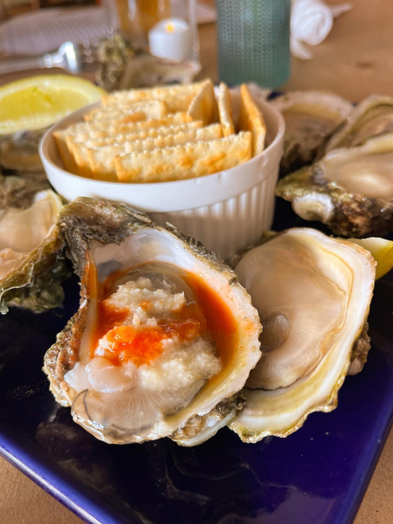 National Oyster Day Shines Bright with the Golden Oyster at Hunt’s in Panama City: A Truly Unforgettable Celebration 9 A close-up of raw oysters topped with horseradish and hot sauce, served with saltine crackers and lemon wedges at Hunt's Oyster Bar in Panama City, Florida for National Oyster Day.