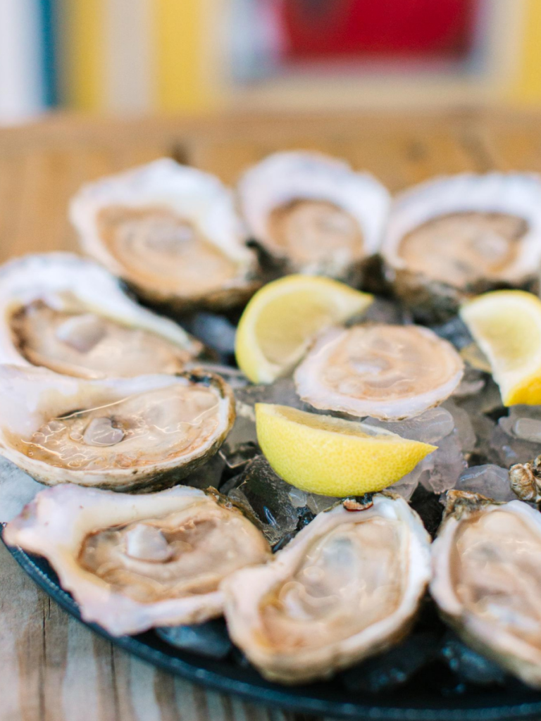 National Oyster Day Shines Bright with the Golden Oyster at Hunt’s in Panama City: A Truly Unforgettable Celebration 10 A close-up view of freshly shucked oysters on ice with lemon wedges at Hunt's Oyster Bar in Panama City, Florida for National Oyster Day.