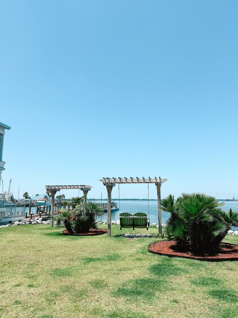 A green Adirondack swing next to Uncle Ernie’s in Historic St. Andrews, a charming relaxing spot in Panama City with waterfront views.