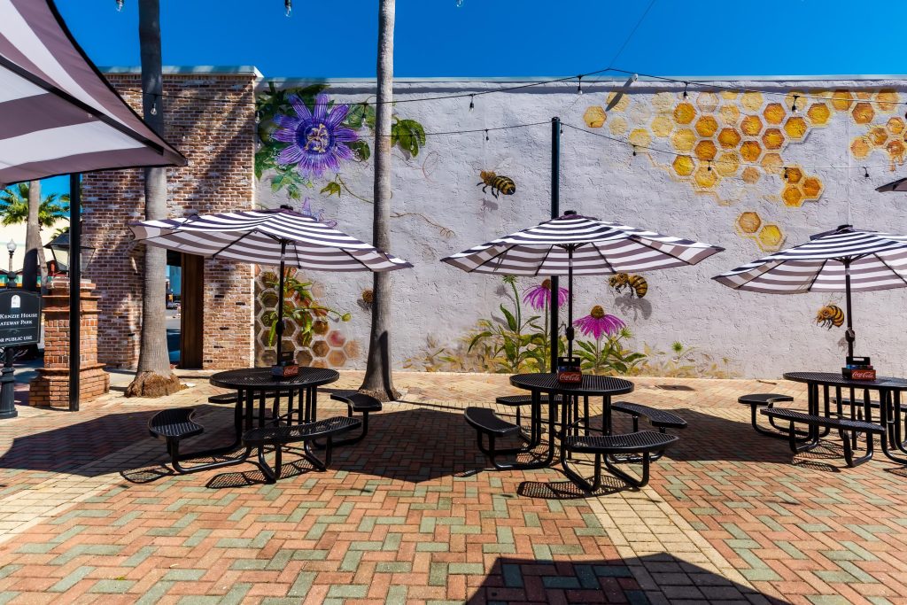 The courtyard at Millie’s, featuring tables with black and white striped umbrellas and the Honey Bee mural, a vibrant relaxing spot in Panama City.