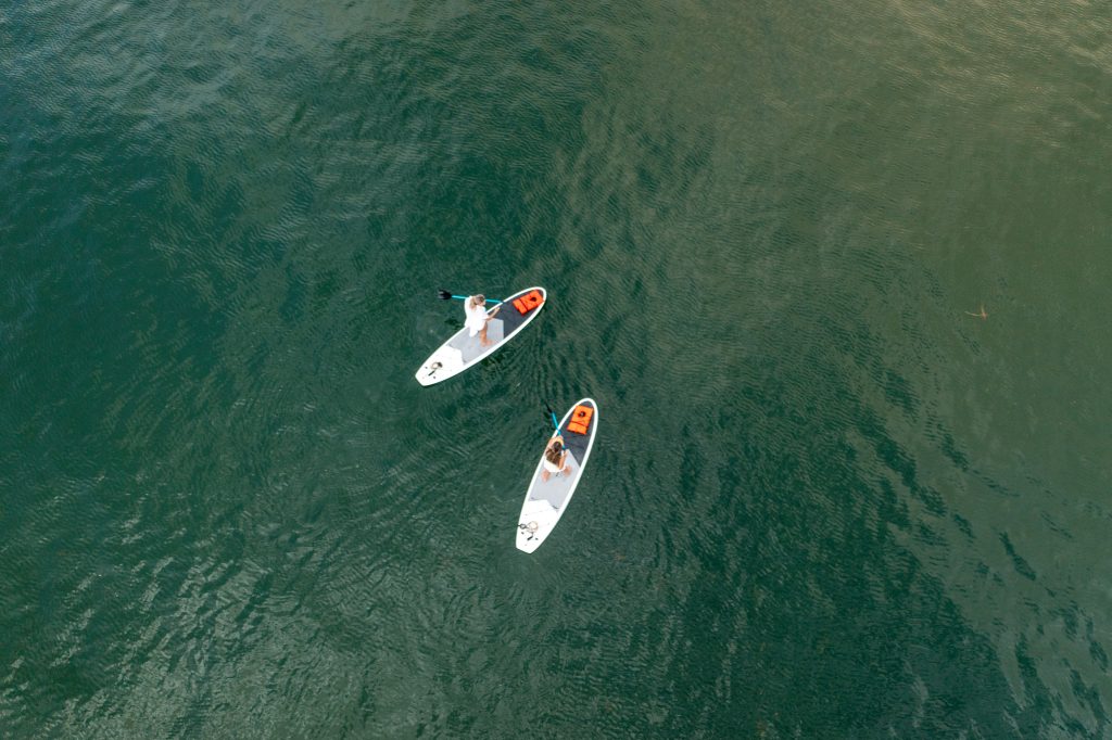 Aerial view of paddleboarders gliding across the clear waters of St. Andrews Bay, offering a peaceful way to enjoy Florida eco-adventures and sustainable travel in Panama City.