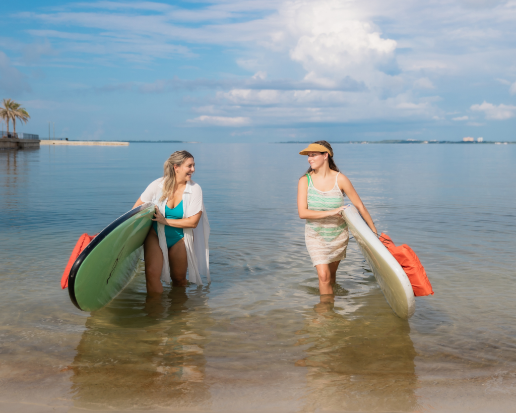 Outdoor & Water Activities in Panama City, Florida 5 Two women walk out of the bay with paddleboards after enjoying water activities in Panama City, Florida.