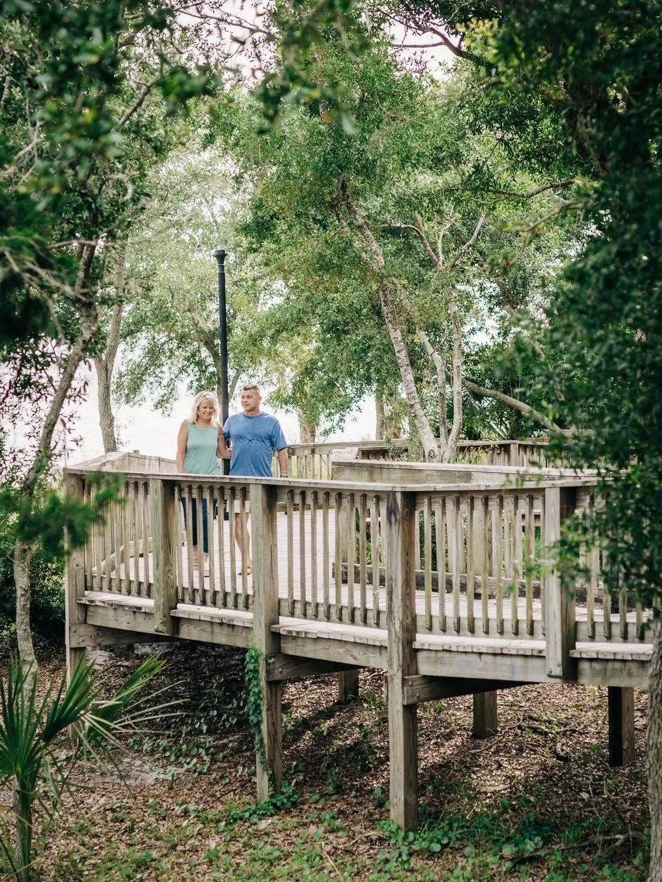 Couple walking along the wooden dune boardwalk at Oaks by the Bay Park in Historic St. Andrews during winter in Panama City