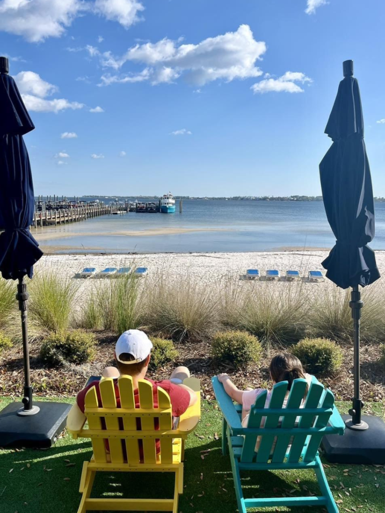 Top 10 Activities for a Family-Friendly Spring Break in Panama City, Florida 10 Parent and child relaxing in colorful Adirondack chairs overlooking the bayside beach during a family-friendly spring break in Panama City.