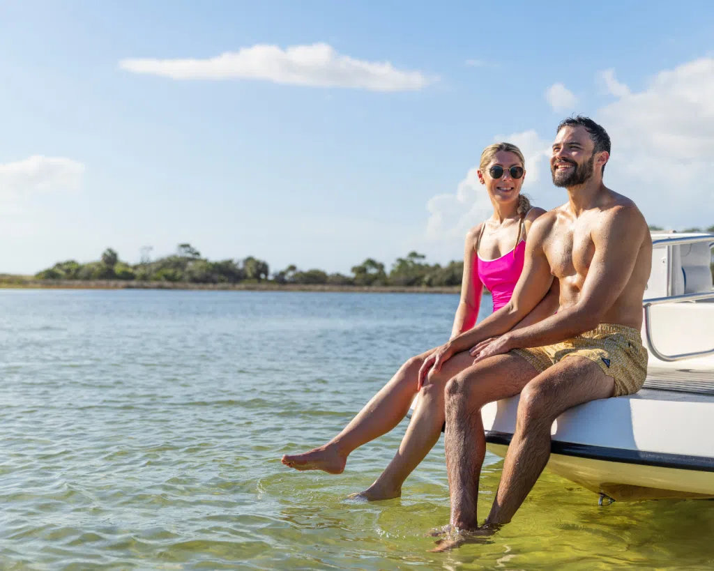 3 Fun Spots for Snorkeling in Panama City, Florida: Where to Go and What to Know 6 Couple relaxing on the edge of a boat in clear bay waters, enjoying a day of snorkeling in Panama City, Florida.