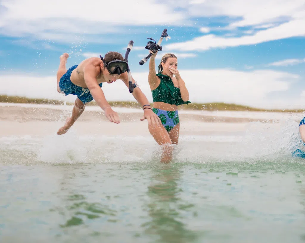 3 Fun Spots for Snorkeling in Panama City, Florida: Where to Go and What to Know 3 Two friends laugh and splash in shallow water while enjoying snorkeling in Panama City, Florida along a sandy shoreline.