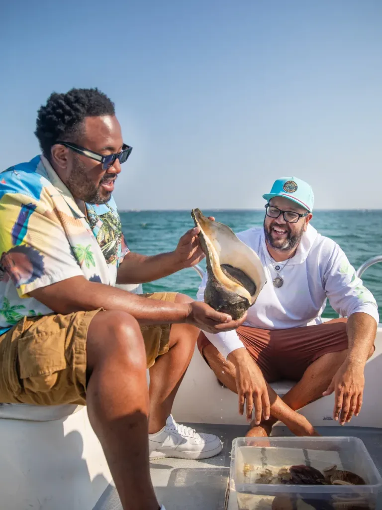 3 Fun Spots for Snorkeling in Panama City, Florida: Where to Go and What to Know 17 Two men on a boat admiring a large seashell after a day of snorkeling in Panama City, Florida.
