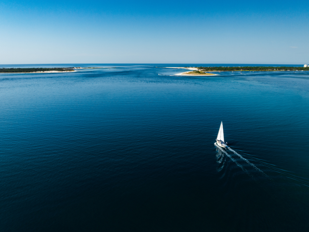 Top Spring Break Outdoor Adventures in Panama City, Florida 5 Spring break outdoor adventures in Panama City featuring a sailboat cruising across the open waters of St. Andrews Bay.