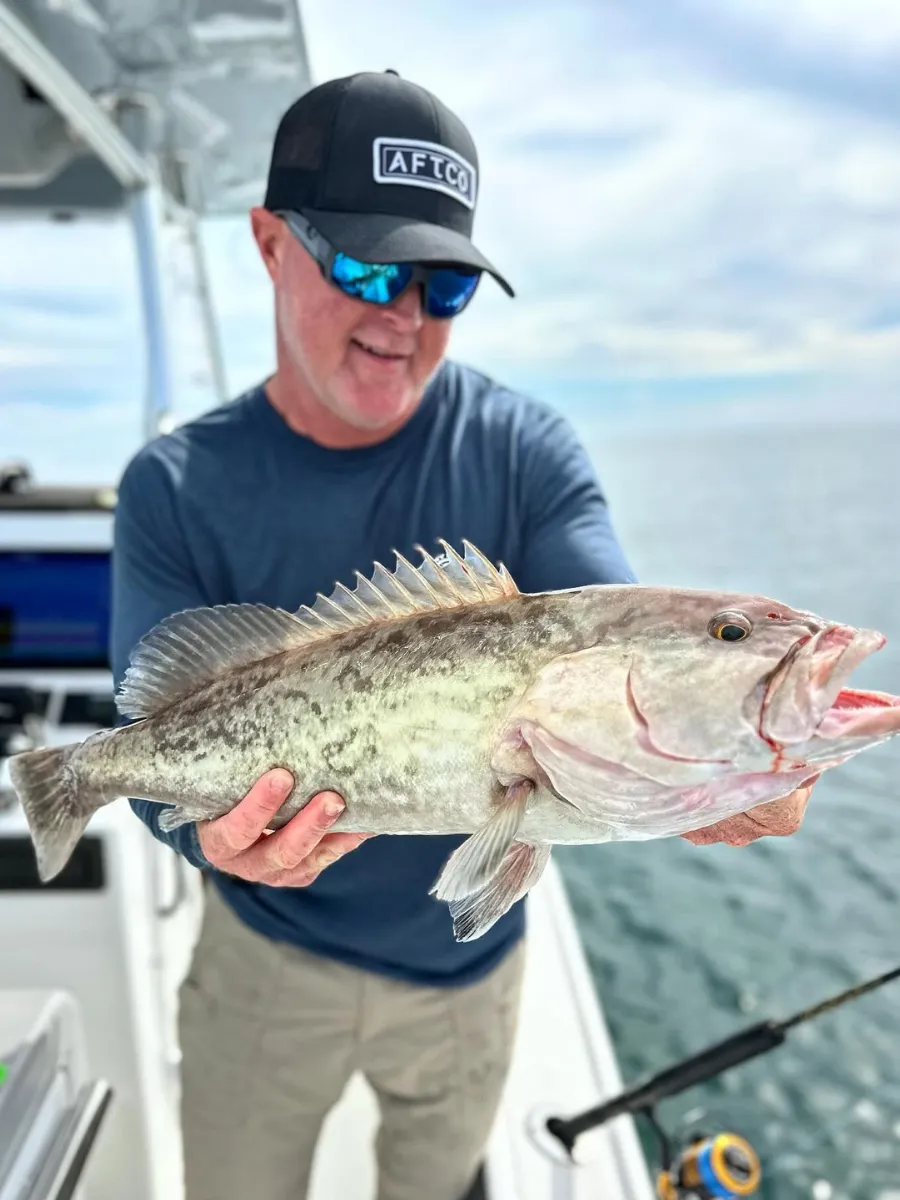 Angler holding a gag grouper caught on an offshore fishing charter, a beginner-friendly hands-on activity in Panama City Florida