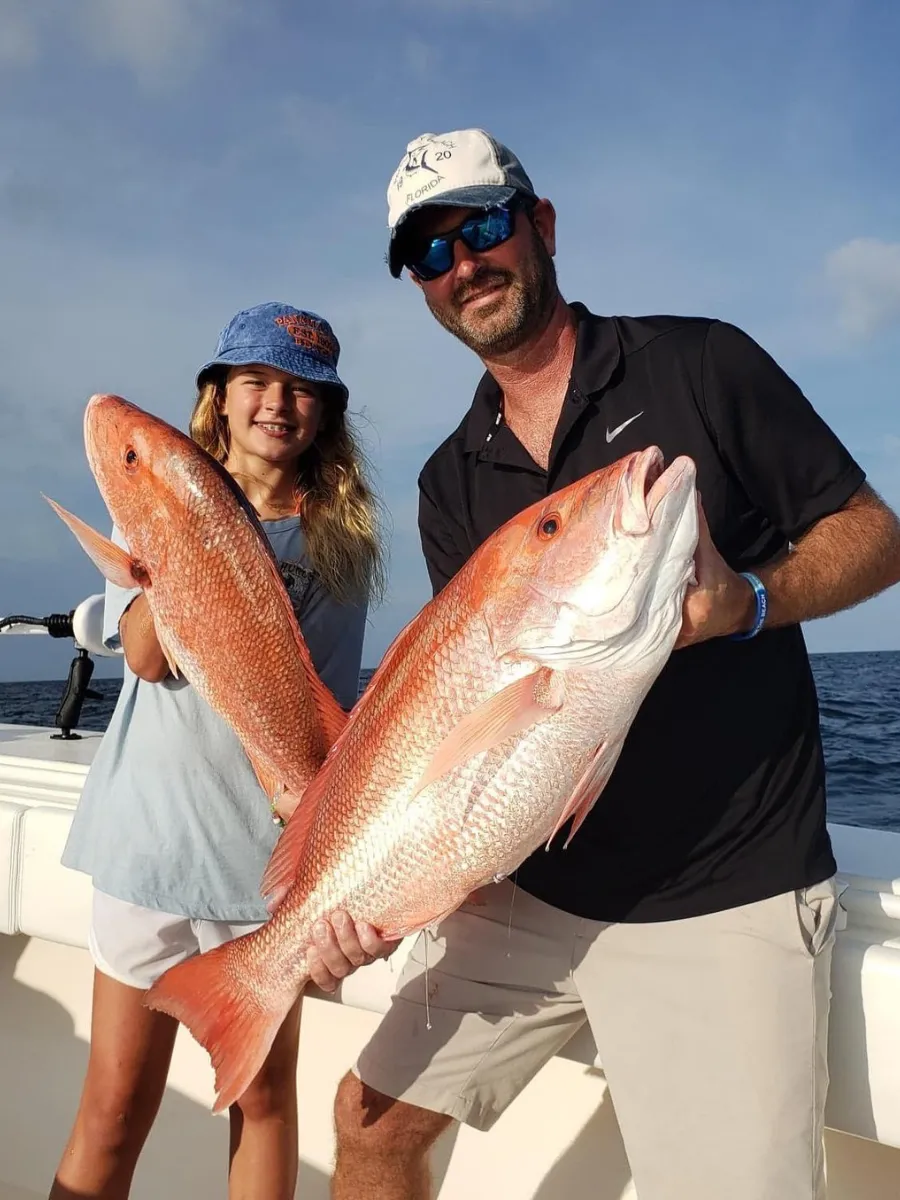 Father and daughter holding red snapper caught on a family fishing charter, one of the best hands-on activities in Panama City Florida