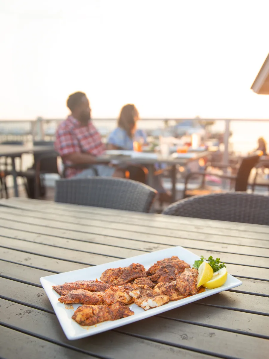 Hook and Cook in Panama City, FL: Where to Bring Your Fresh Catch for Dinner 4 Blackened Gulf fish served at sunset on a waterfront patio, a classic hook and cook meal in Panama City FL