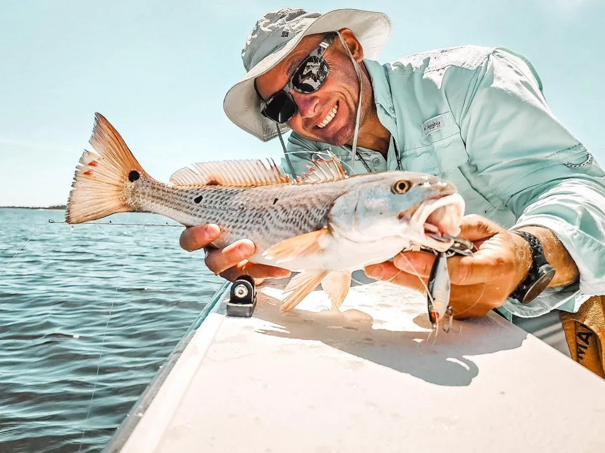 Angler holding a redfish caught on an inshore charter, one of the top types of fishing in Panama City on St. Andrews Bay