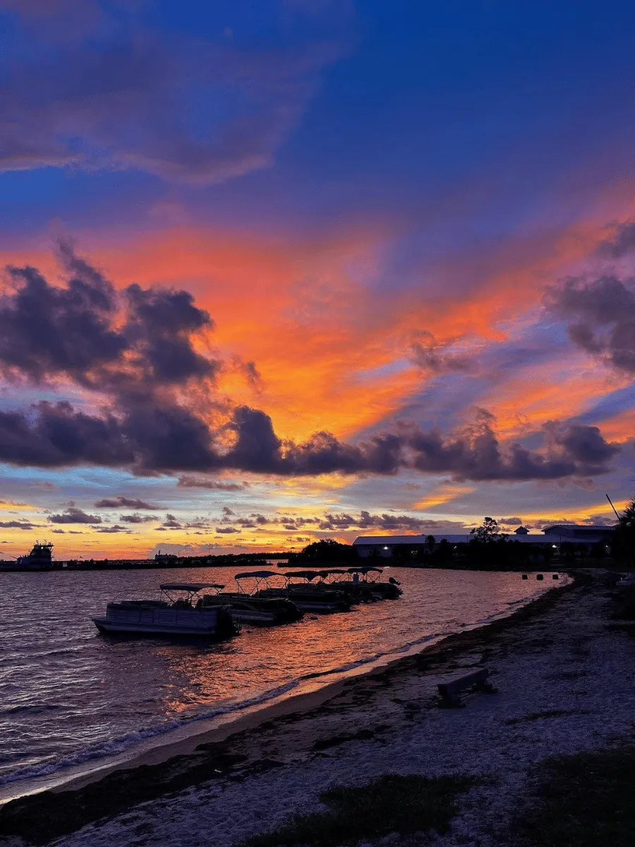 Colorful sunset in Panama City Florida above pontoon boats along a bayside shoreline.