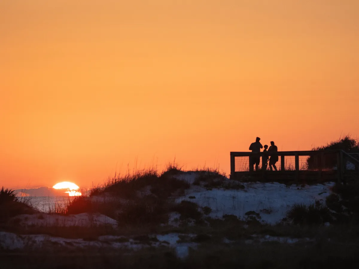 Family watching the sun set over St. Andrews Bay in Panama City Florida.