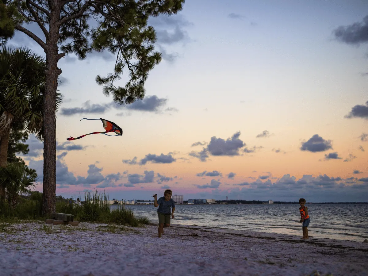 Children playing along a bayside beach during sunset in Panama City Florida.