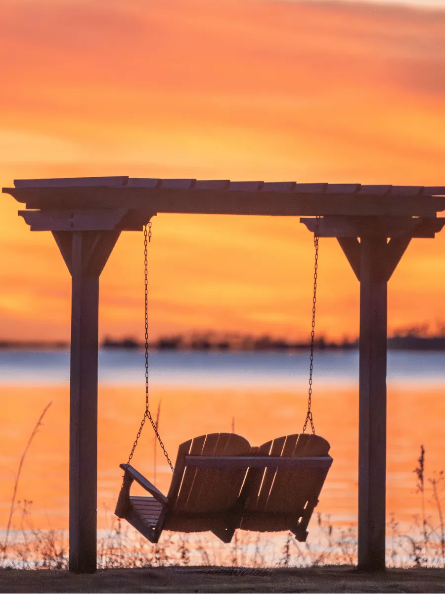 Waterfront swing silhouetted against a glowing sunset in Panama City Florida over St. Andrews Bay.